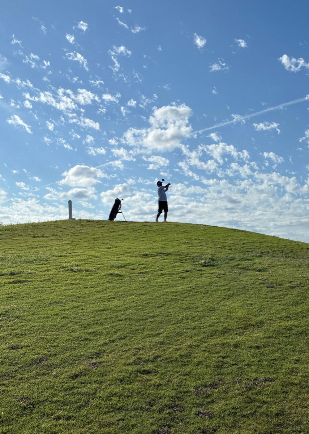 The Backswing — a small figure and a big sky on a golf course